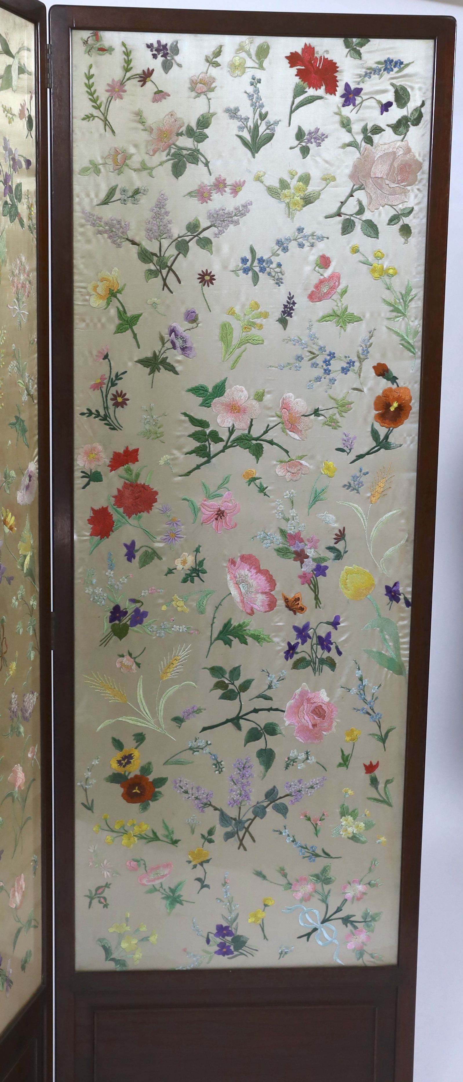 An Edwardian mahogany three fold screen with three panels of later (possibly 1920’s) hand embroidered, multi coloured, silk flowers, 50.5cm wide x 139cm high